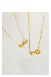 Close-up of infinity symbol gold necklace with zircon stones on a cream fabric