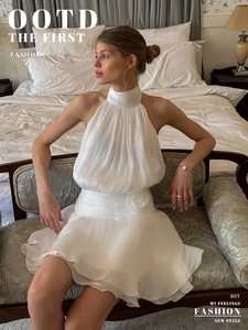 Detail of white halter mini dress with pleated fabric and 3D floral waist decoration
