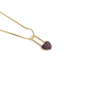 Detail shot of golden box chain necklace with ruby heart lock pendant on white background