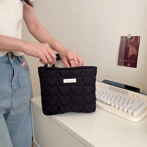 Vista dettagliata della pochette trapuntata a cuori neri con toppa logo bianca in un set vita