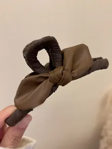 Dettaglio del fermaglio per capelli vintage con fiocco in pelle bicolore marrone
