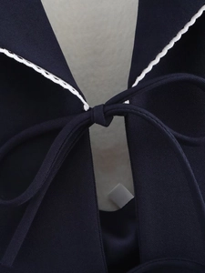 Détail de l'encolure dos nu bleu foncé avec dentelle ondulée blanche et ruban noué