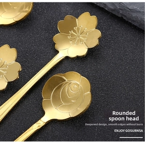 Detail of polished gold cherry blossom and rose shaped stainless steel dessert spoons