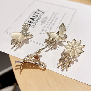 Elegant gold metal butterfly and flower hair clips with opal stones on a display card