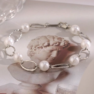 Detail of white pearls and hammered silver links laid on classical art background