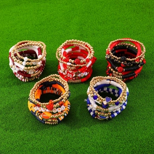 Stack of 5 Game Day heishi clay bead bracelets for football fans on green turf