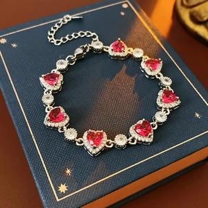 Detail eines silbernen Armbands mit roten Zirkon-Herzen auf einer Luxus-Geschenkbox