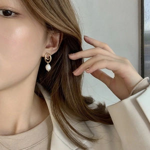 Close-up of golden double-loop pearl earrings worn to show the elegant hanging style