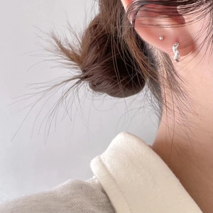 Close-up of minimalist twisted 925 sterling silver hoop earring on a model ear