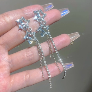 Macro shot of silver sparkling double star tassel earrings with shimmering crystals