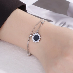 Double-layered silver bracelet with sun flower pendant on woman's wrist