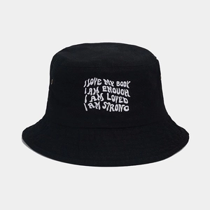Gros plan sur la broderie de lettres blanches sur le chapeau bob en toile noire