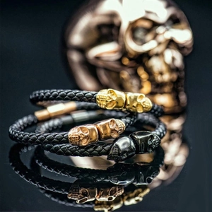 Three braided leather bracelets with gold, rose gold and black steel skull beads