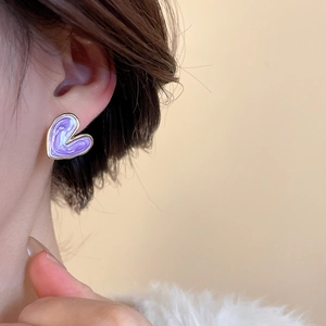 Close-up of a model wearing a purple enamel heart stud earring with golden edges