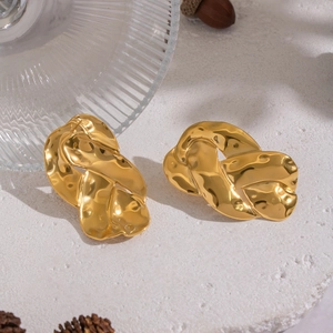 Vue détaillée de boucles d'oreilles dorées géométriques sur un socle en pierre grise