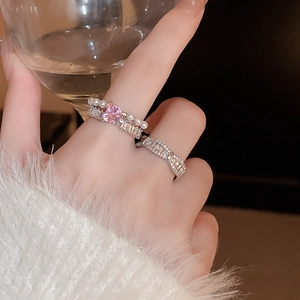 Gros plan de bagues empilables avec cœur rose et perles sur le doigt
