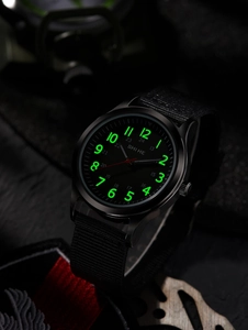 Tactical black watch with green luminous numerals and red second hand on rock background