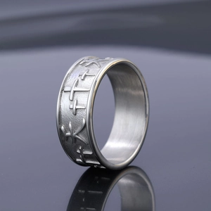 Vintage stainless steel ring with embossed cross and character pattern on silver band