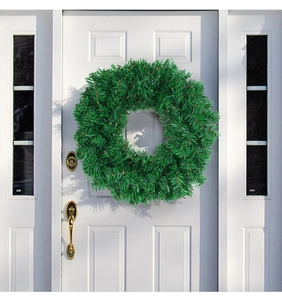 Detail of a green artificial Christmas wreath hanging on a white door with gold handle