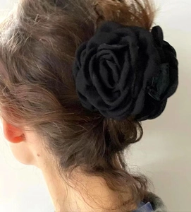 Detail view of a black fabric rose hair claw clip worn on a model's hair from the back
