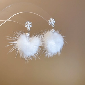 Dettaglio degli orecchini con pompon a cuore bianco, perla e motivo a fiocco di neve