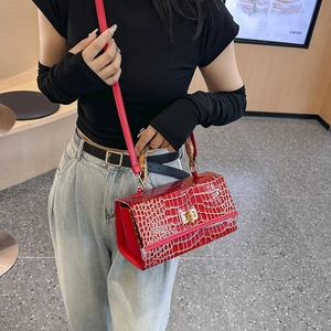 Detail of red crocodile pattern bag featuring bamboo handle and golden twist lock clasp