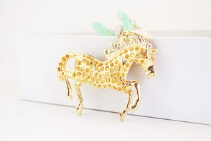 Detailed close-up of golden horse-shaped keychain pendant with hollow running design