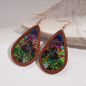 Detail of bohemian teardrop wood earrings with colorful mosaic patterns on marble
