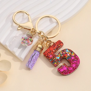 Close-up of number 5 resin keychain with pink glitter, purple tassel and glass orb