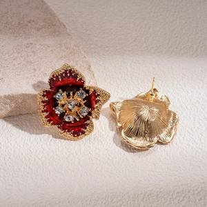 Close-up of vintage flower earrings with red enamel petals and crystals on a stone base