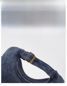 Macro detail of adjustable bronze metal buckle on vintage washed navy cotton baseball cap