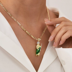 Close-up of gold St. Jude necklace with green enamel and sparkling stones on model