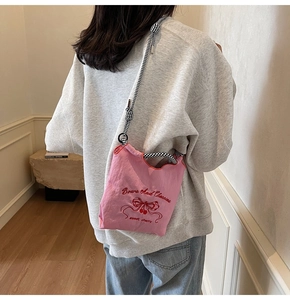 Pink nylon crossbody bag with cherry embroidery and braided strap on model