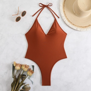 Flat lay of rust red halter neck swimsuit with summer beach straw hat and sunglasses