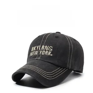 Detail of white embroidery text on a vintage washed cotton black baseball cap