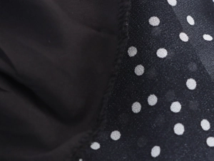Macro detail of black polka dot chiffon fabric with high-quality stitching texture