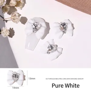 Detailed view of translucent white resin bow nail charms with heart rhinestone center