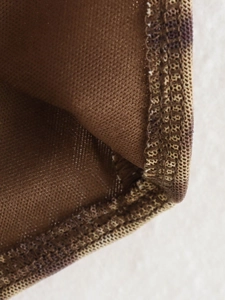 Close-up of brown mesh knit fabric with detailed stitching on short denim romper