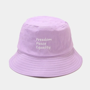 Détail de la broderie blanche Freedom Peace Equality sur un bob en coton violet clair
