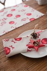 Close-up of Christmas table mat with red candy patterns on natural linen texture fabric