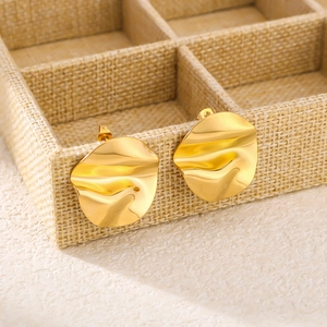 Macro detail of 18K gold plated irregular round ruffled earrings in a linen jewelry box