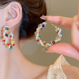 Detailed view of handmade pearl and colorful crystal beaded hoop earrings on model