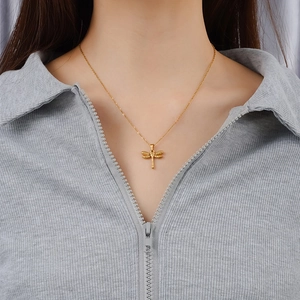 Minimalist 18K gold dragonfly pendant necklace worn by a model on a grey background