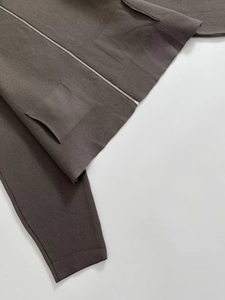 Detail of taupe knit cardigan showing silver zipper, ribbed cuffs, and fine fabric texture