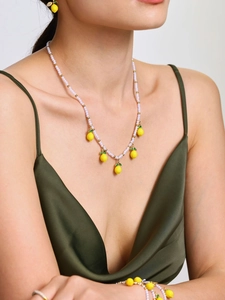 Modella che indossa set di gioielli con limone e perle, collana e orecchini a perline