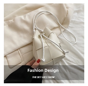 Detailed macro view of beige woven bucket bag with drawstring closure and wide leather straps