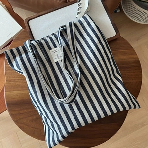 Gros plan détaillé d'un grand cabas en toile à rayures noires et blanches sur une table