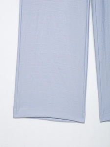 Detailed close-up of light blue wide-leg trousers showing premium fabric texture and hem stitching