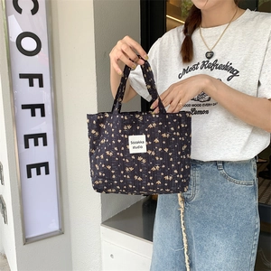 Detail of dark blue quilted floral canvas tote bag featuring white woven brand label