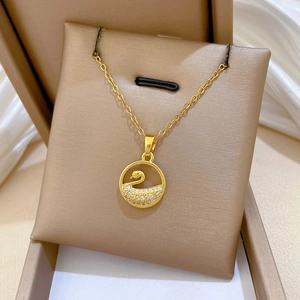 Macro shot of gold swan necklace with sparkling crystals on jewelry display card